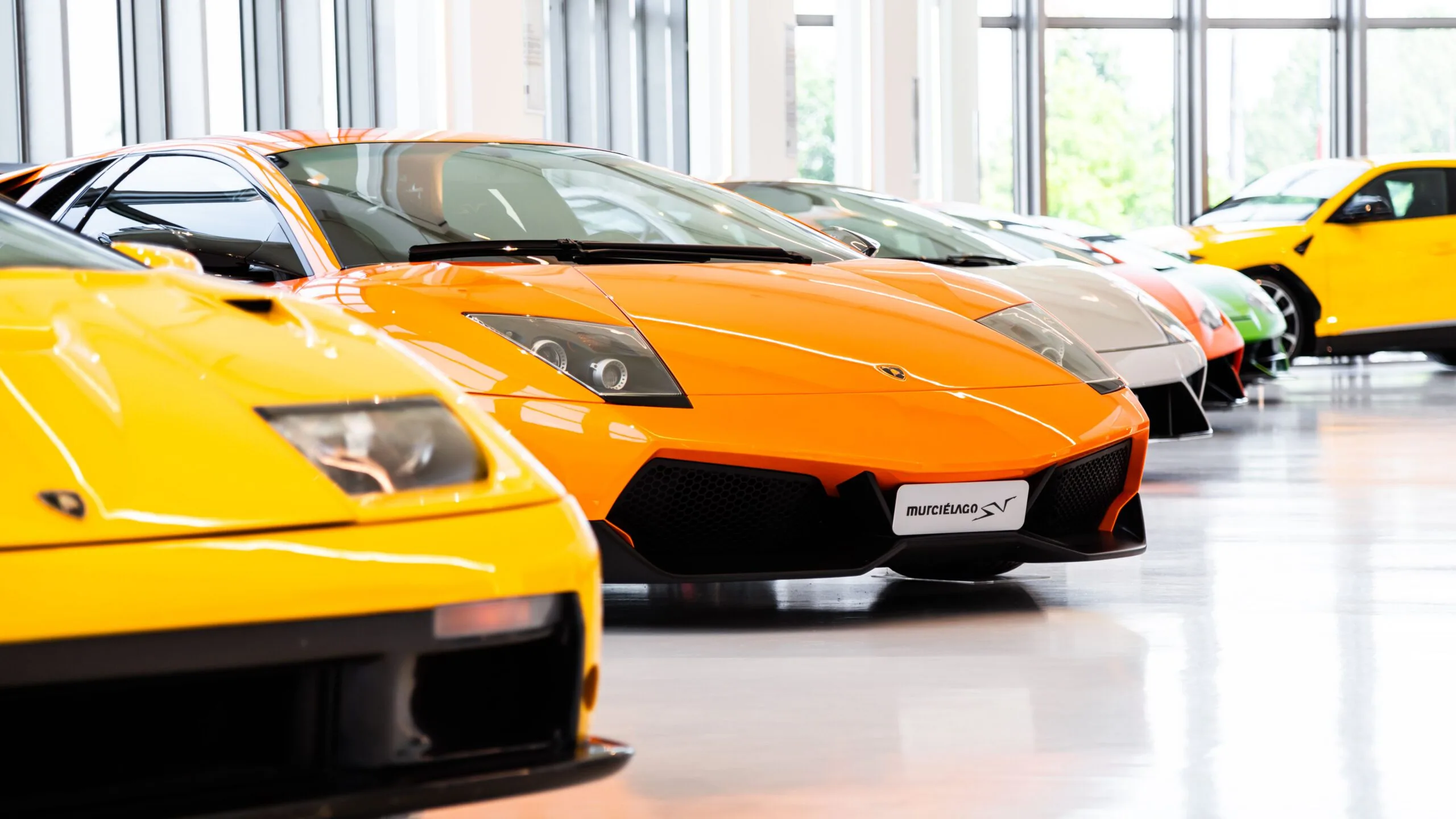 A row of exotic cars parked in a rental operator showroom